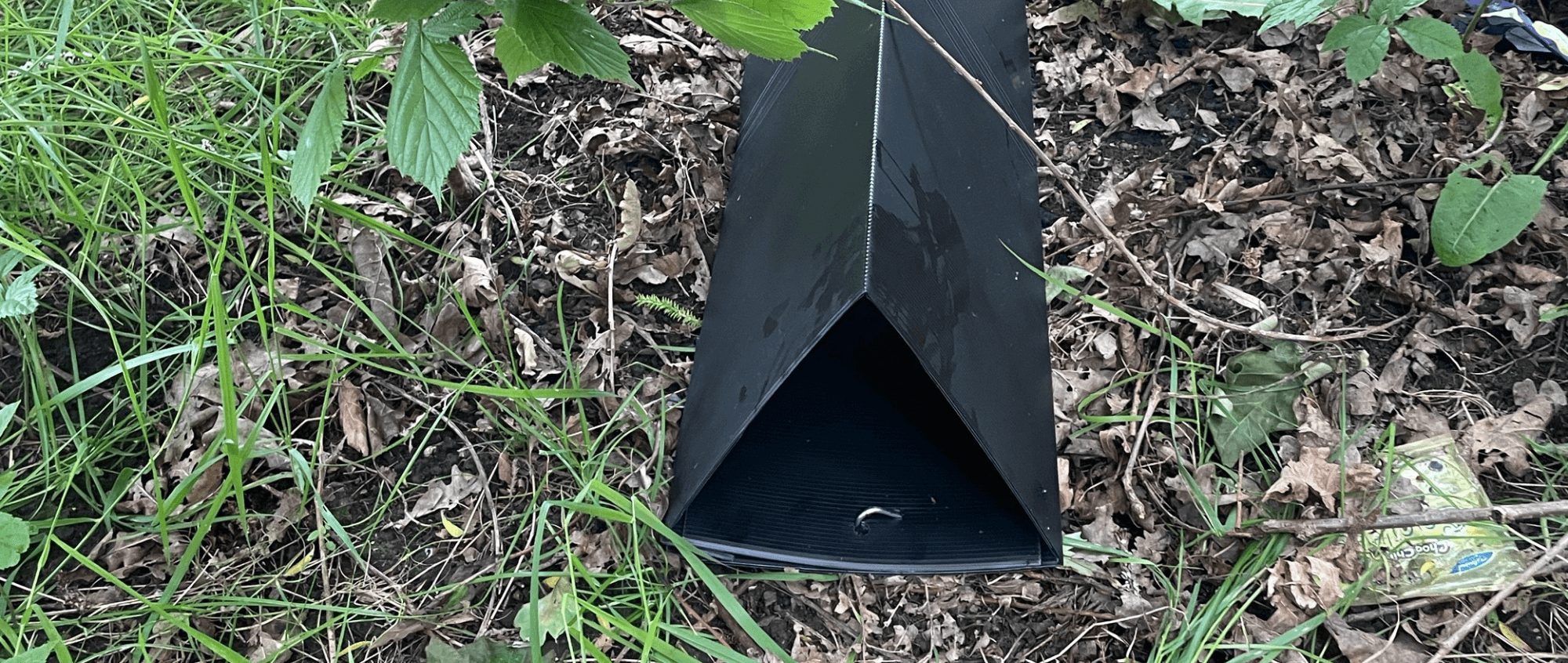 a black plastic triangular tunner lays on some grass