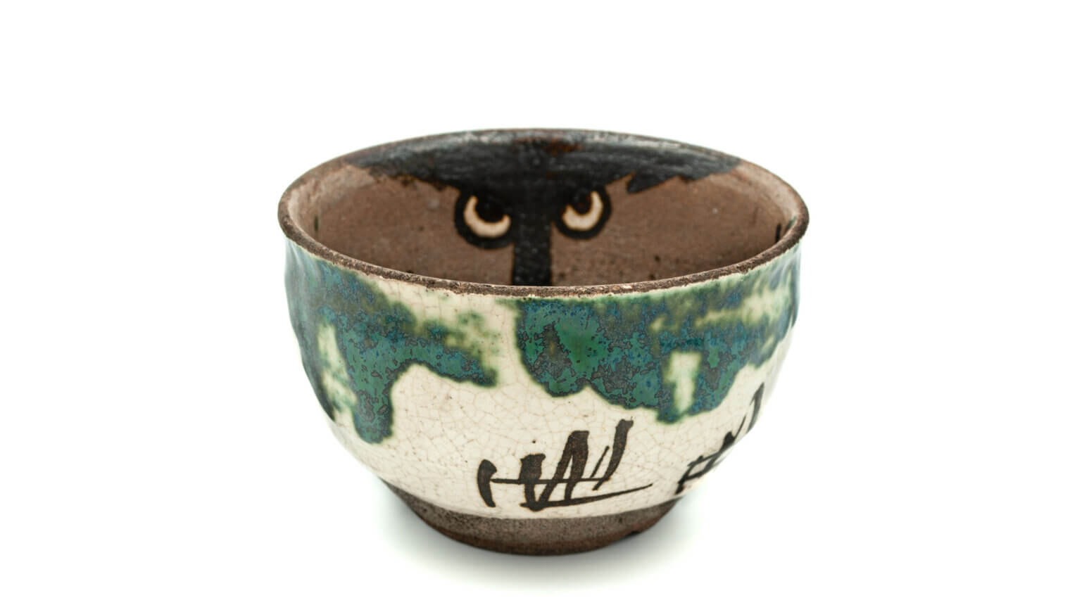 A white and green Japanese bowl. The inside of the bowl is painted to look like the face of a brown tiger.