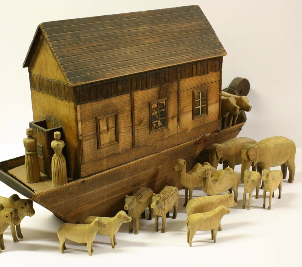 A wooden toy ark with pairs of different wooden animals lined up beside it.