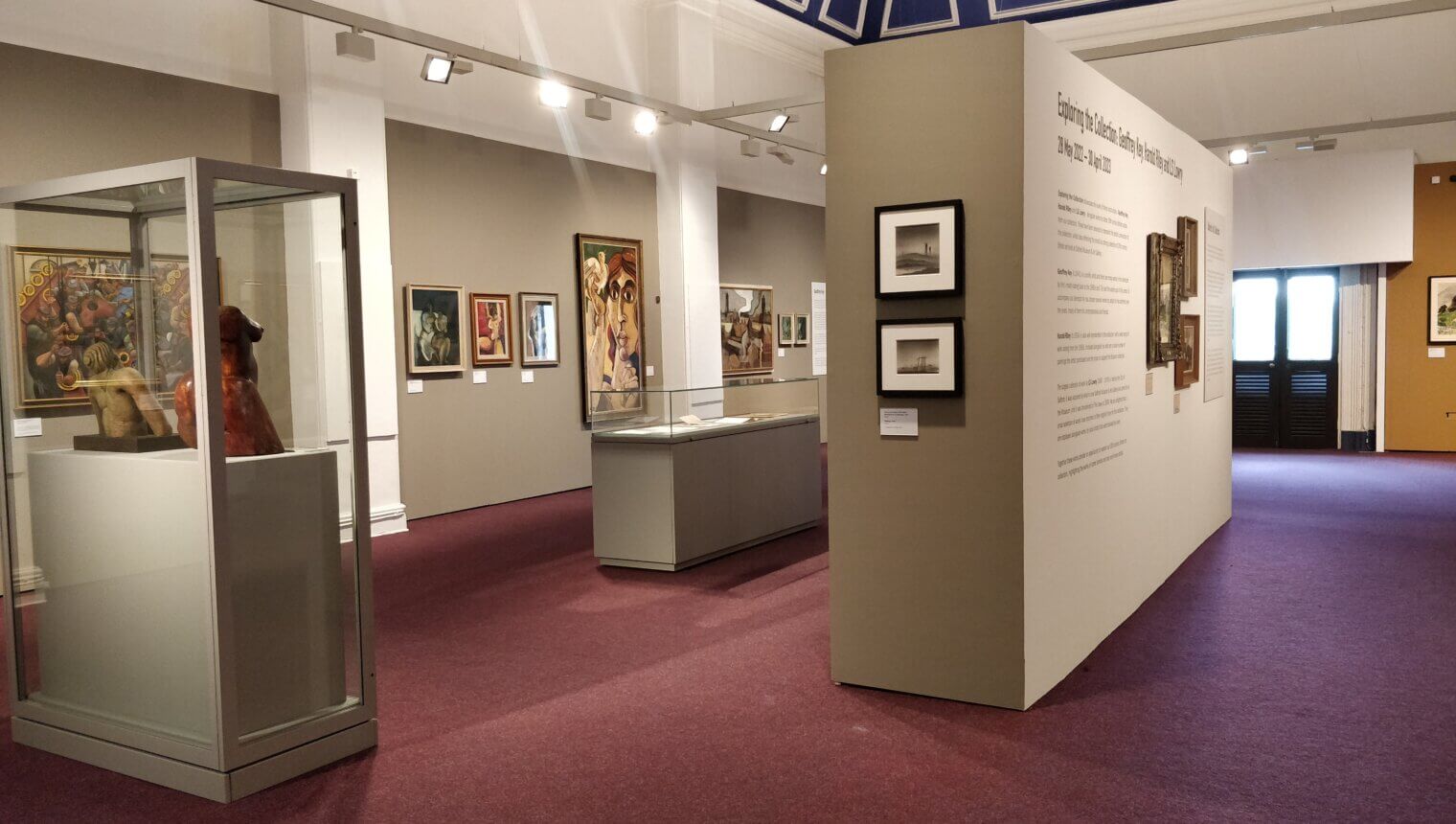 Beige walls with framed paintings hanging on them.