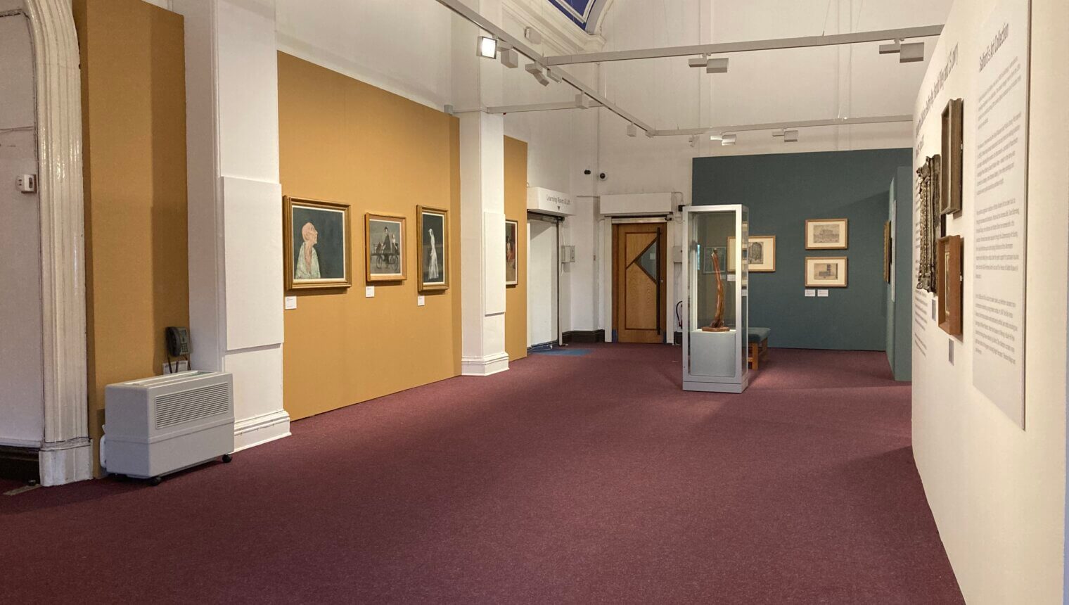 Yellow, blue, and white walls with framed paintings hanging on them.