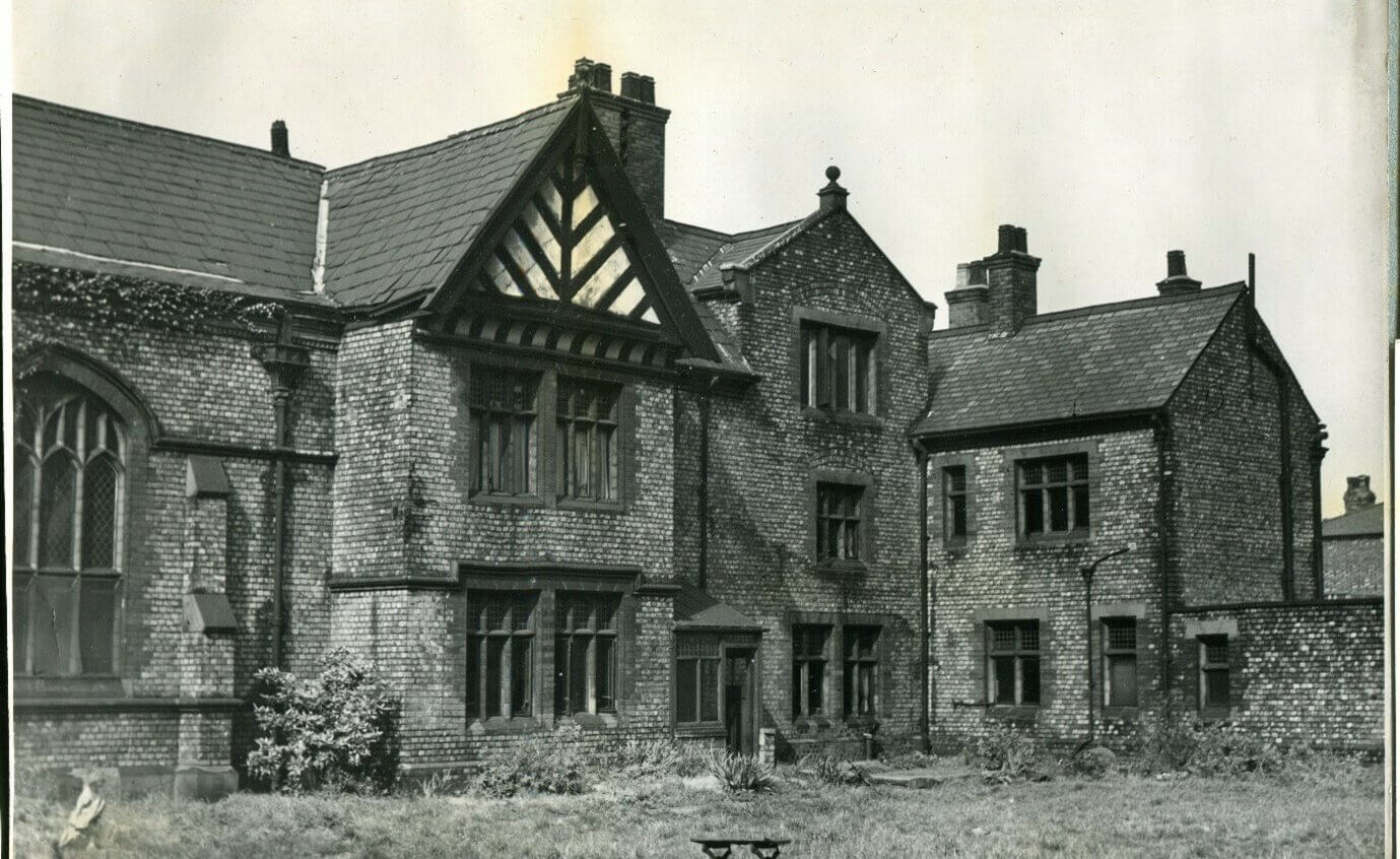 A black and white photograph of Ordsall Hall, a large building with a Tudor roof.