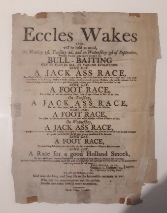 An old piece of paper showing the itinerary for Eccles Wakes, 1800. The paper lists Bull-Bating, a Jack Ass race, a foot race, and a race for a good Holland Smock on the 2nd and 3rd of September.