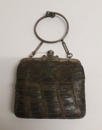 A bag made of a black, leathery material. It has a metal clasp and handle.