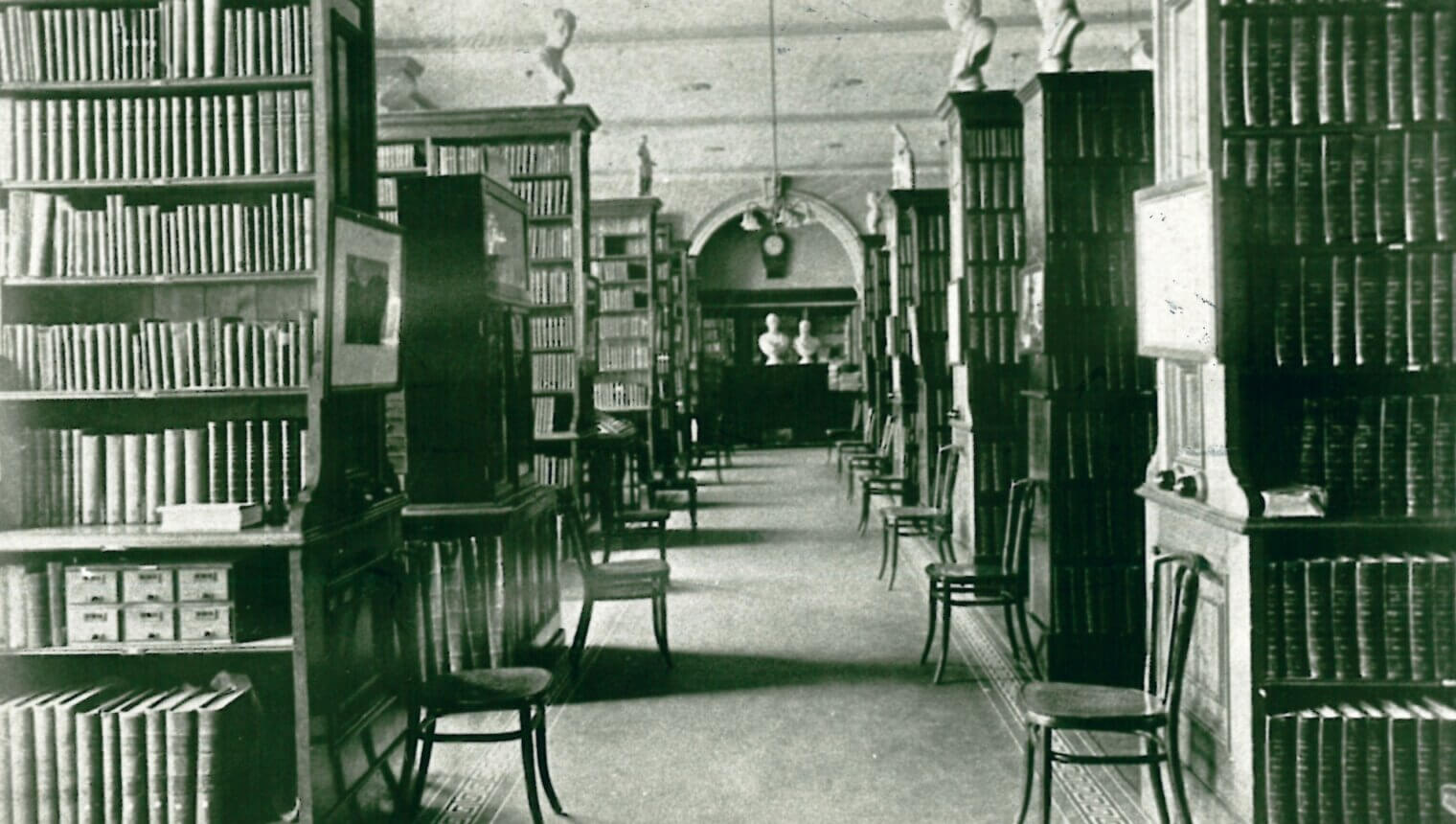 A library with aisles of books and reading chairs.