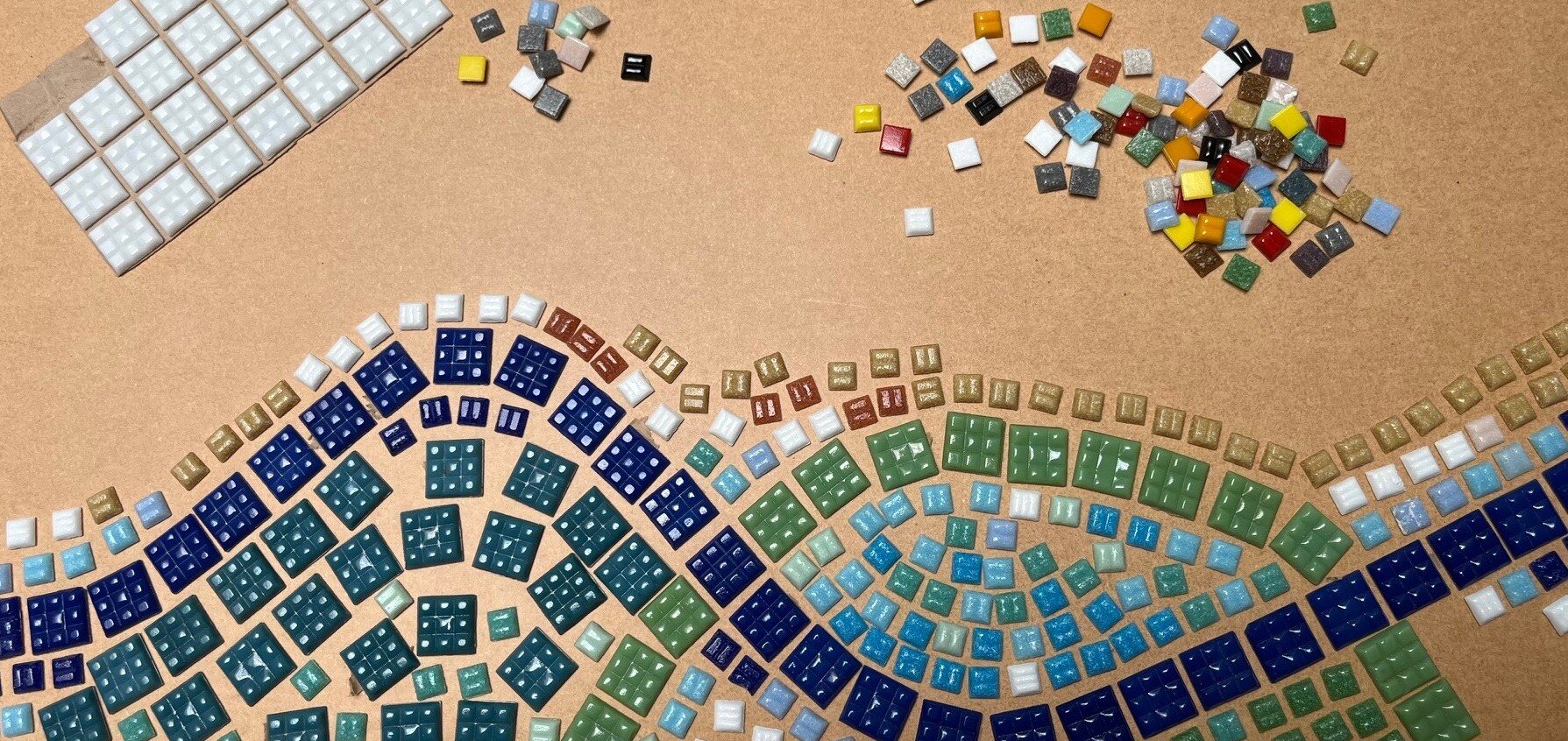 Different coloured tiles are laid out to look like waves on a beach.