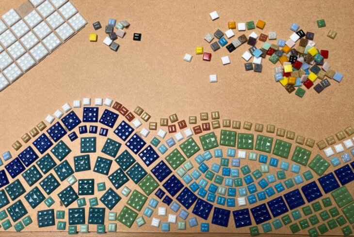 Different coloured tiles are laid out to look like waves on a beach.