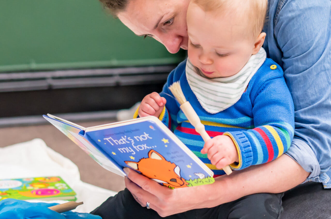 Parent with young baby reading a book